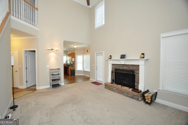 living room with carpet, a fireplace, crown molding, and a towering ceiling