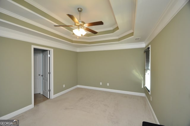 carpeted spare room with ceiling fan, a raised ceiling, and ornamental molding