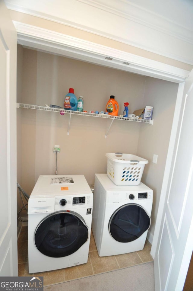 washroom featuring ornamental molding, washing machine and dryer, and light tile patterned floors