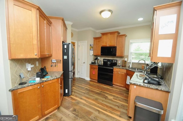 kitchen featuring sink, black appliances, crown molding, light stone counters, and dark hardwood / wood-style flooring