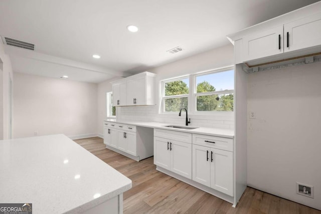 kitchen with white cabinetry, light hardwood / wood-style flooring, and sink