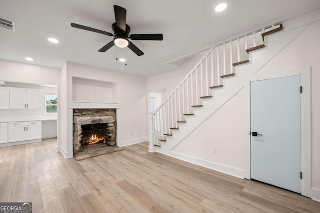 unfurnished living room with ceiling fan, a fireplace, and light hardwood / wood-style flooring