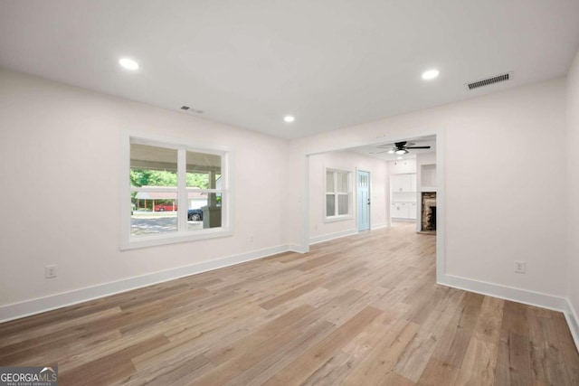 unfurnished living room featuring ceiling fan, a fireplace, and light hardwood / wood-style flooring