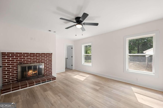 unfurnished living room with ceiling fan, light hardwood / wood-style floors, and a brick fireplace