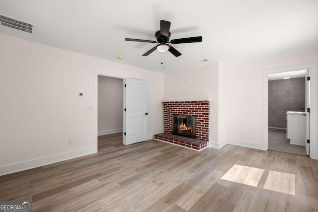 unfurnished living room featuring light hardwood / wood-style flooring, ceiling fan, and a fireplace