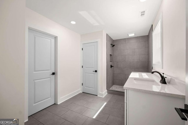 bathroom with tile patterned floors, a tile shower, and vanity