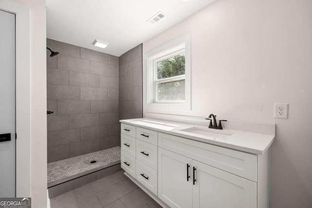 bathroom with tiled shower, tile patterned flooring, and vanity