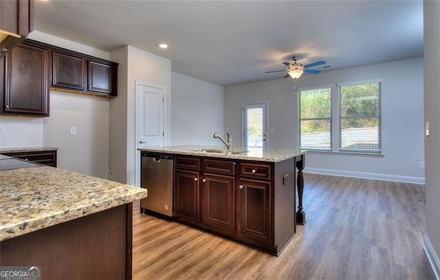 kitchen with ceiling fan, light stone counters, sink, stainless steel dishwasher, and a kitchen island with sink