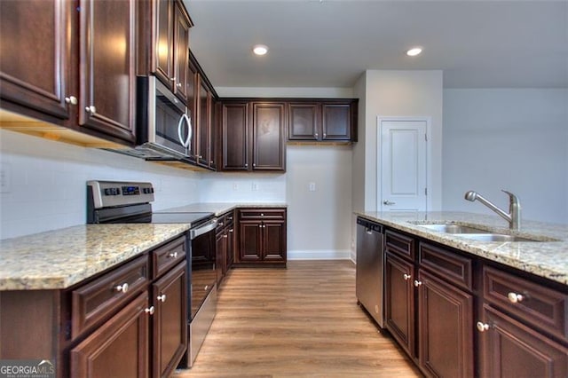 kitchen with light stone counters, sink, light hardwood / wood-style flooring, stainless steel appliances, and backsplash