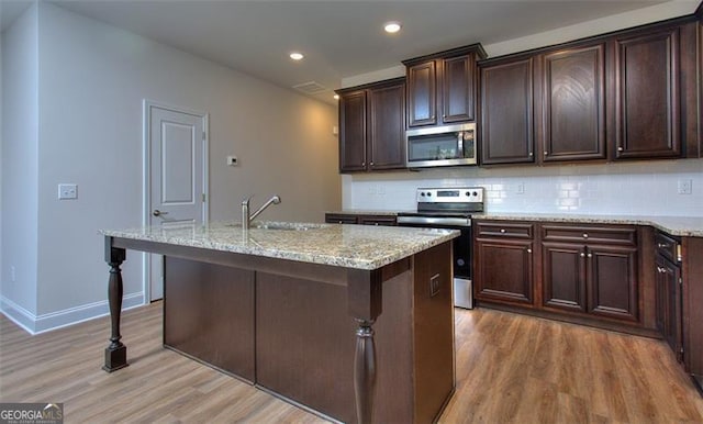 kitchen featuring appliances with stainless steel finishes, a kitchen island with sink, sink, and hardwood / wood-style flooring