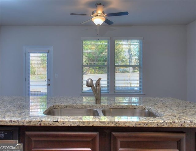 room details featuring ceiling fan, light stone countertops, and sink