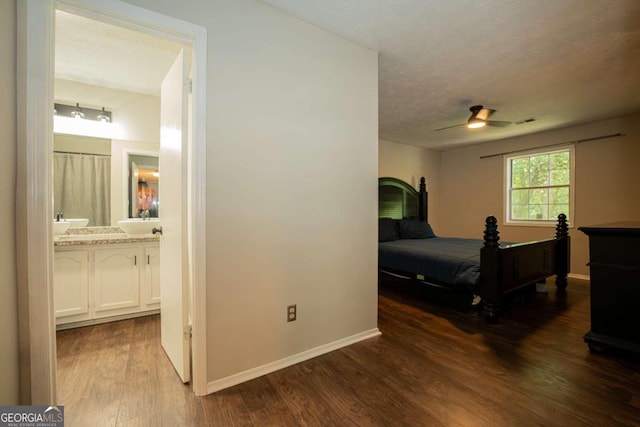 bedroom featuring ceiling fan, sink, a textured ceiling, dark wood-type flooring, and ensuite bathroom