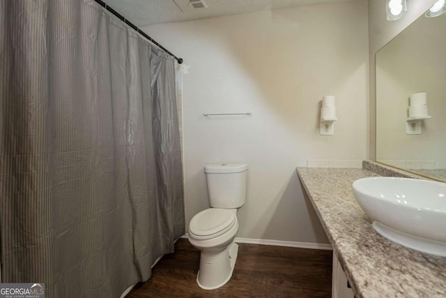 bathroom with vanity, toilet, curtained shower, a textured ceiling, and hardwood / wood-style floors