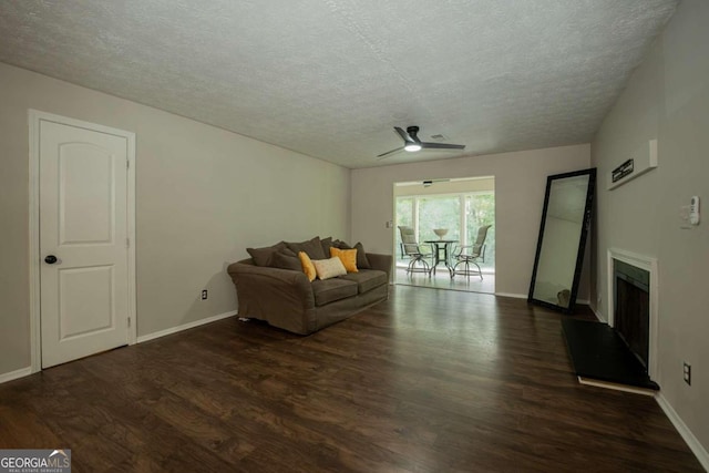 living room featuring ceiling fan, a textured ceiling, and dark hardwood / wood-style flooring