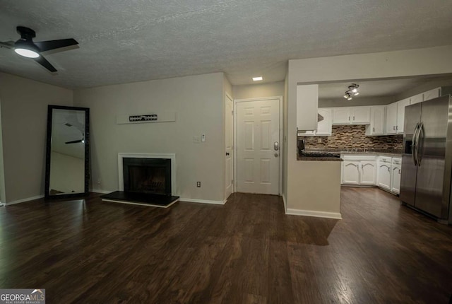 unfurnished living room with ceiling fan, a textured ceiling, and dark hardwood / wood-style flooring