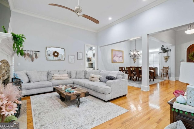 living room featuring ceiling fan with notable chandelier, ornamental molding, and light hardwood / wood-style floors