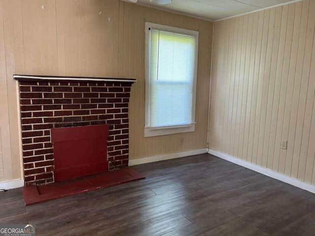 unfurnished living room featuring wooden walls and dark hardwood / wood-style flooring