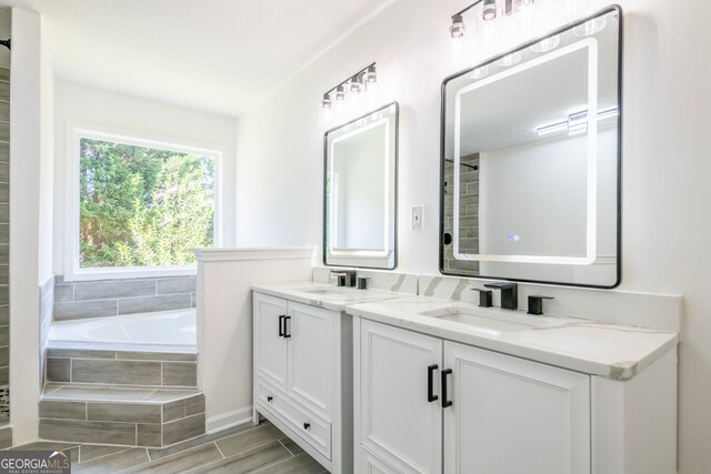 bathroom featuring wood-type flooring, tiled bath, and vanity