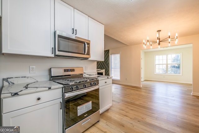 kitchen with light wood-type flooring, white cabinets, stainless steel appliances, and a chandelier