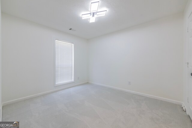 carpeted empty room featuring a textured ceiling