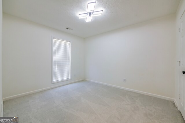 spare room with light carpet and a textured ceiling