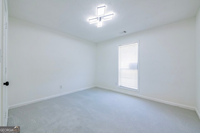 empty room featuring a textured ceiling and carpet