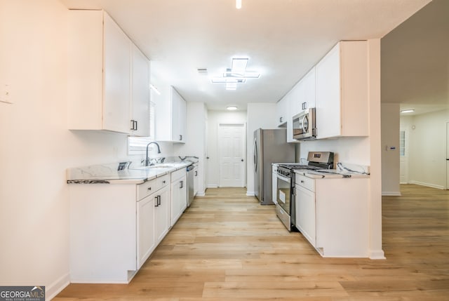 kitchen with light wood-type flooring, appliances with stainless steel finishes, white cabinetry, and sink