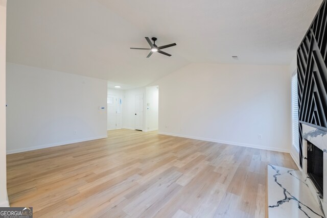 unfurnished living room featuring ceiling fan, a fireplace, light hardwood / wood-style floors, and vaulted ceiling