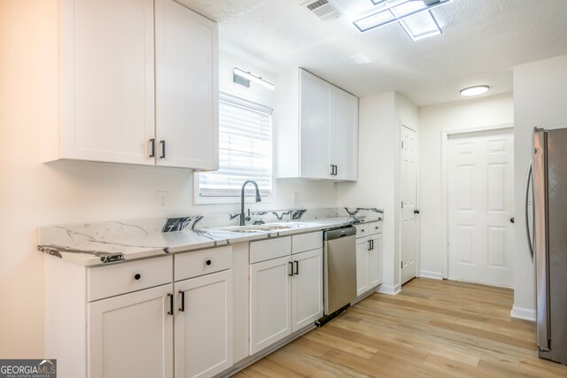 kitchen featuring light wood-type flooring, appliances with stainless steel finishes, and white cabinetry