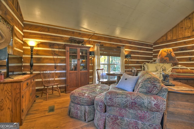 living room featuring hardwood / wood-style floors, wood walls, and vaulted ceiling