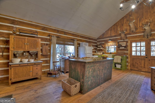 kitchen featuring lofted ceiling, wood walls, a kitchen island, wood-type flooring, and white refrigerator