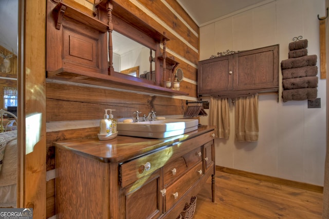 bathroom with hardwood / wood-style floors, vanity, and wood walls