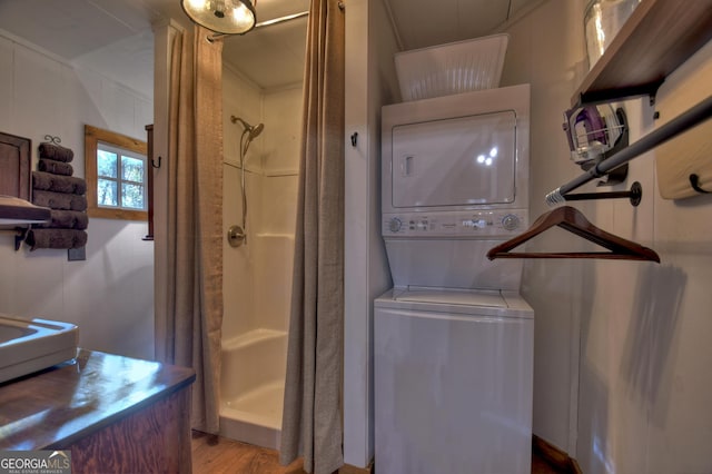 bathroom featuring a shower with shower curtain, stacked washer / drying machine, and hardwood / wood-style floors