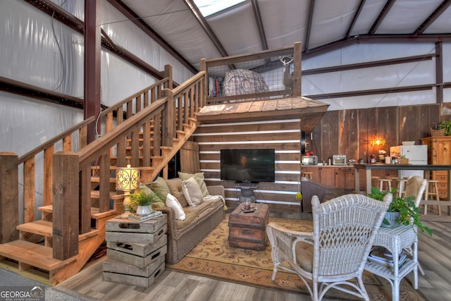 living room with lofted ceiling, hardwood / wood-style flooring, and wooden walls