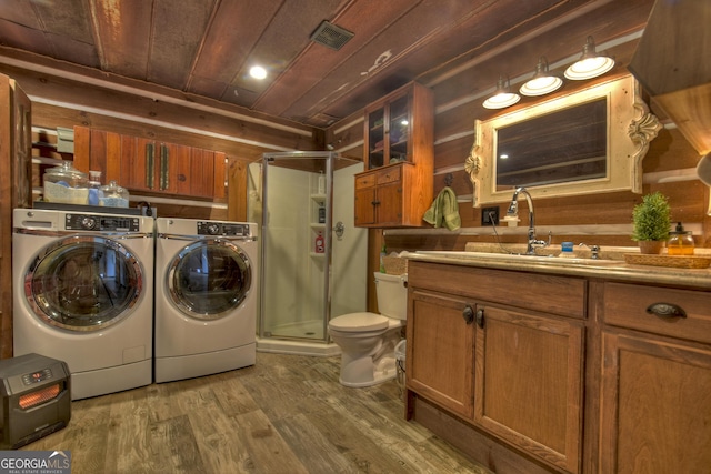 laundry room with hardwood / wood-style flooring, wooden walls, wooden ceiling, washing machine and dryer, and sink