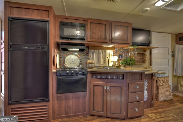 kitchen with range with gas cooktop, exhaust hood, dark wood-type flooring, sink, and fridge