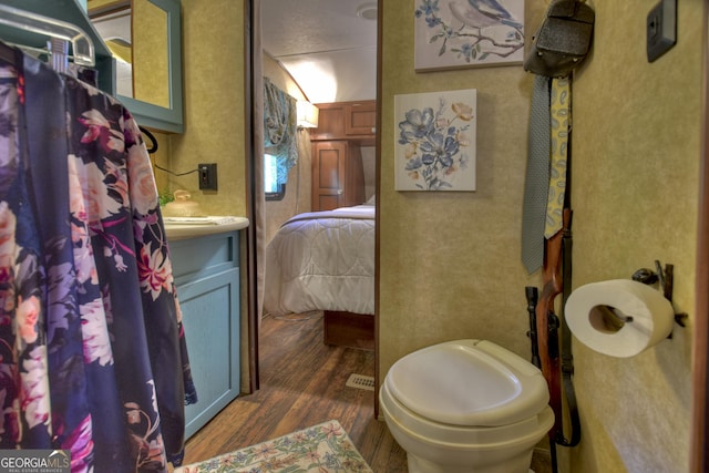 bathroom featuring toilet, vanity, and hardwood / wood-style floors