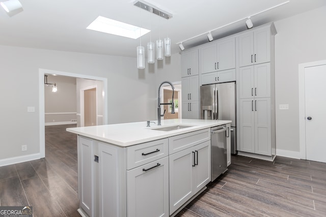 kitchen with dark hardwood / wood-style flooring, lofted ceiling with skylight, a center island with sink, stainless steel dishwasher, and sink