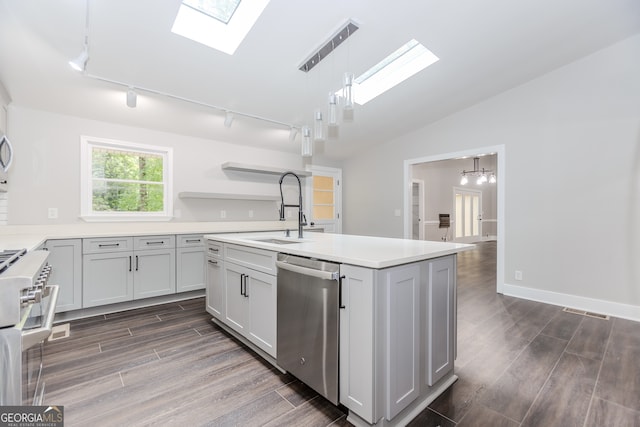 kitchen featuring dark hardwood / wood-style floors, lofted ceiling with skylight, appliances with stainless steel finishes, hanging light fixtures, and sink