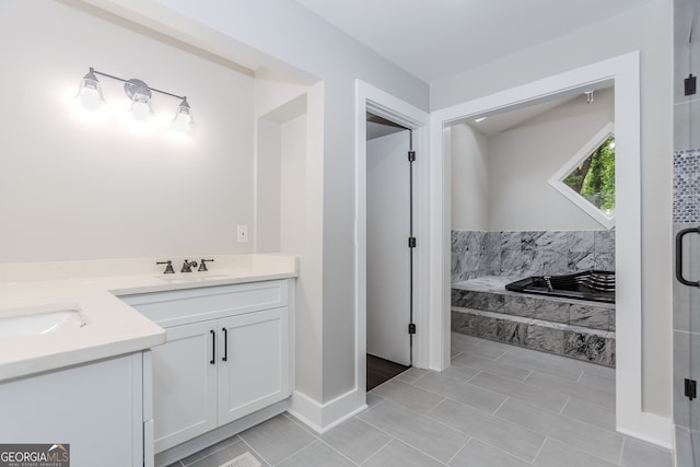 bathroom with vanity, tile patterned flooring, and tiled bath