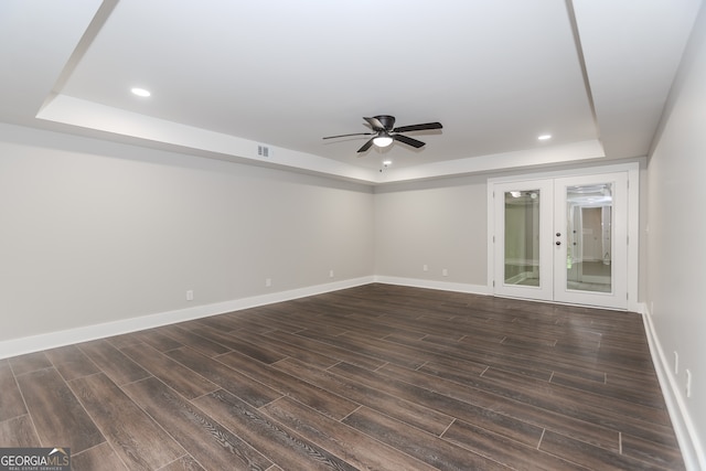 unfurnished room with a tray ceiling, french doors, ceiling fan, and dark hardwood / wood-style floors