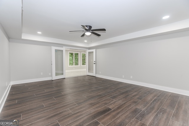 interior space featuring dark wood-type flooring, ceiling fan, and a raised ceiling