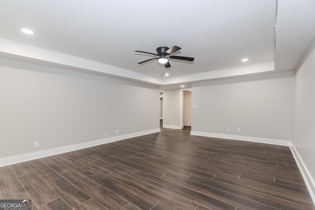 unfurnished room featuring dark wood-type flooring, ceiling fan, and a tray ceiling