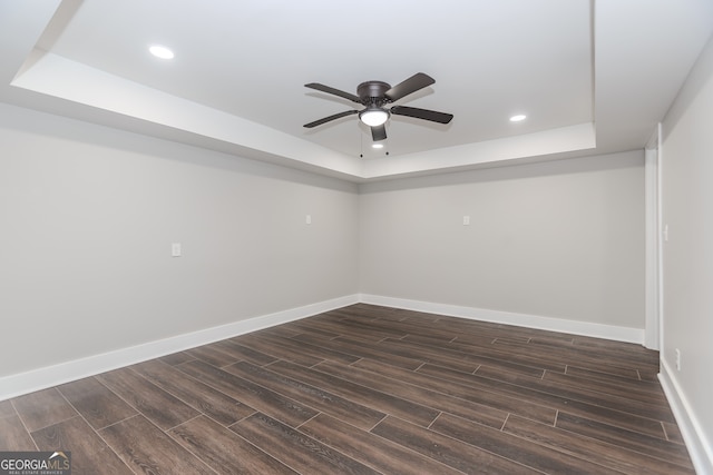 spare room with ceiling fan, a raised ceiling, and dark hardwood / wood-style flooring