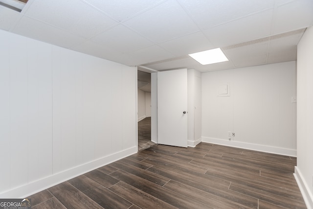 basement with dark wood-type flooring and a paneled ceiling