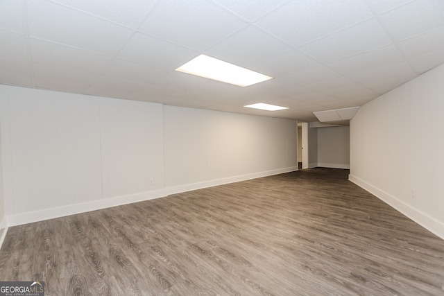 basement with a paneled ceiling and wood-type flooring