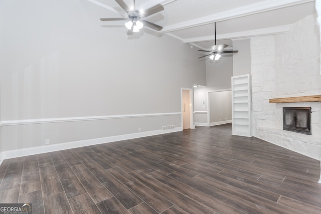 unfurnished living room with dark hardwood / wood-style floors, a fireplace, beam ceiling, high vaulted ceiling, and ceiling fan