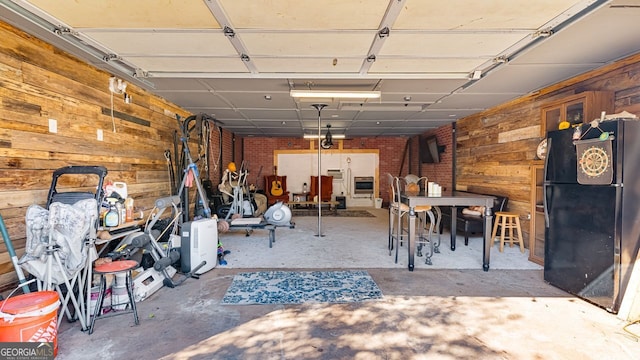 garage with wood walls and black fridge