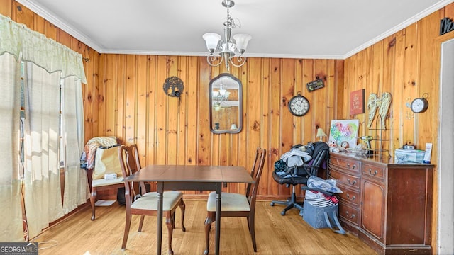 dining space with wood walls, light hardwood / wood-style floors, crown molding, and a notable chandelier