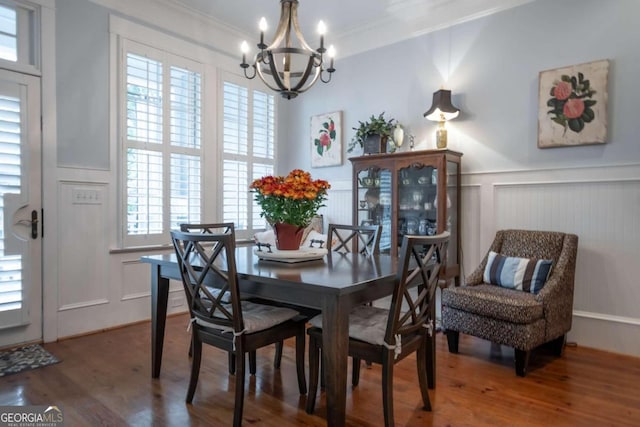 dining space with ornamental molding, a notable chandelier, and wood-type flooring